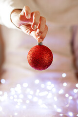 woman hands holding christmas ball on blurred background. Copy space