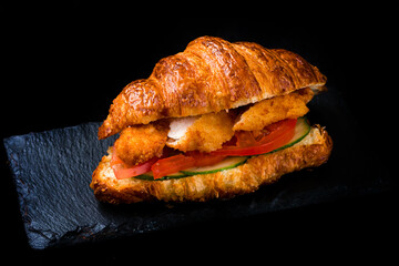 Fresh French croissant with breaded fried chicken, tomatoes, cucumbers and sauce.