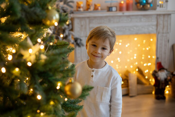 Cute preschool child, blond boy with pet dog, playing in decorated Christmas room