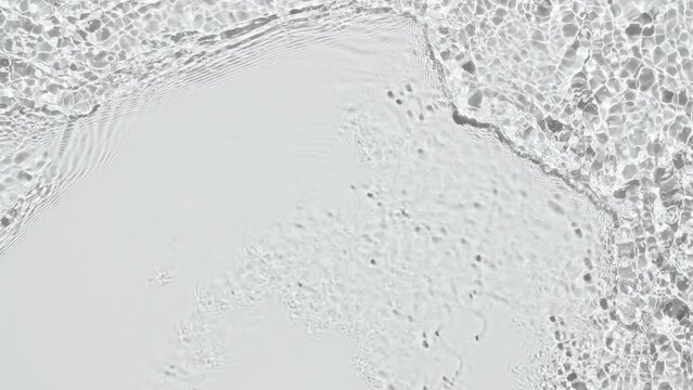 Pure water with reflections sunlight in slow motion. Water surface texture top view. Sun and shadows. Motion clean swimming pool ripples and wave. High quality 4k footage