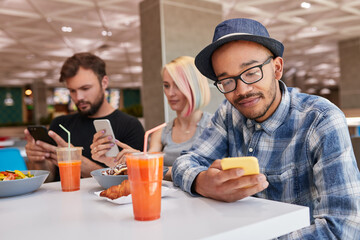Black man using smartphone near friends