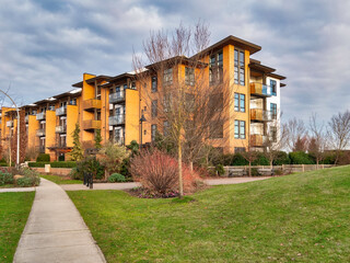 Concrete pathway across green lawn in front of residential condo building - obrazy, fototapety, plakaty