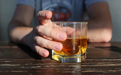 man holds a glass of whiskey. rest at the bar. alcohol addiction. full glass of whiskey in a male hand