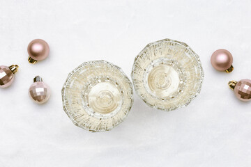 Minimal New Year background, two glass white sparkling wine, trend glasses champagne top view, small Christmas balls, beige golden monochrome aesthetic background, holiday event concept