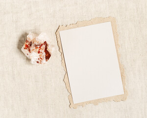 Square invitation card mock up, blank greeting card and protection crystal, healing stone quartz on table. Torn paper. Minimal business brand template. Flat lay, top view, copy space