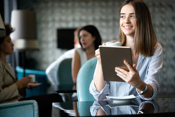 Young female entrepreneur reading electronic book on digital tablet in modern restaurant