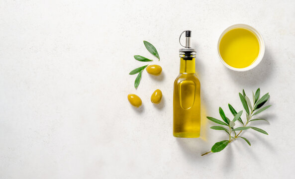 Olives and olive oil in white bowl with bottle of olive oil on white background. Mockup for package. Copy space.