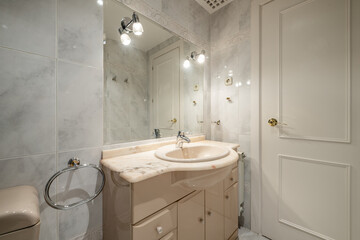 Classic bathroom with cream sanitary ware, beveled mirror embedded in the wall with white wooden door