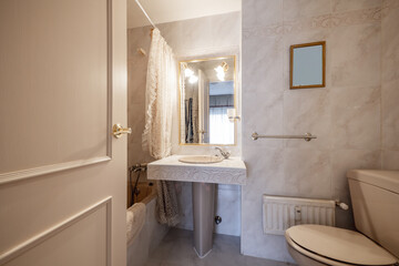 Bathroom with gold-framed mirrors on the walls covered in marble-effect stoneware, cream marble floors with matching countertop with porcelain base