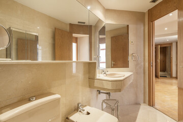 Fototapeta na wymiar Bathroom with large mirrors on the walls that are clad in cream marble and floors of the same