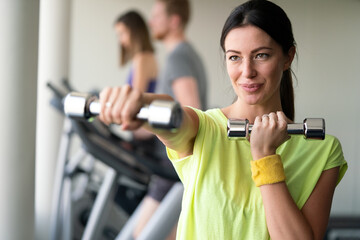 Attractive young woman working out with dumbbells at a gym.