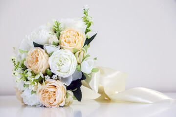 A beautiful bouquet of wedding flowers featuring white and peach roses, isolated against white background, symbol of love, romance and marriage.