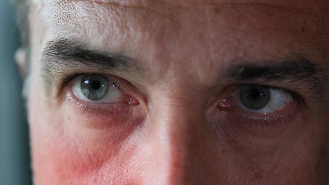 Detail shot of mature caucasian man's blue-green eyes illuminated by siren light