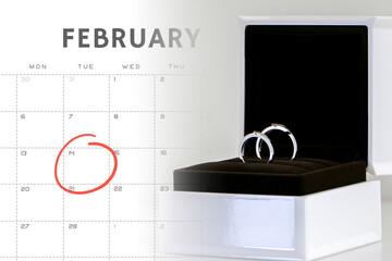 Couple of exquisite shiny wedding rings displayed in open ring box over February calendar with 14th Valentine’s day marked in a circle. Valentines, love, romance and wedding concept.