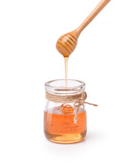 Glass jar of pure honey with honey dipper isolated on white background.