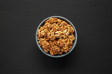 Raw Organic Walnuts in a Bowl on a black background, top view. Flat lay, overhead, from above.