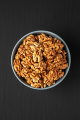 Raw Organic Walnuts in a Bowl on a black background, top view. Flat lay, overhead, from above.