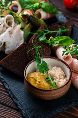 Horseradish and mustard in a bowl with pieces of lard, bacon, herbs, pickles and croutons.