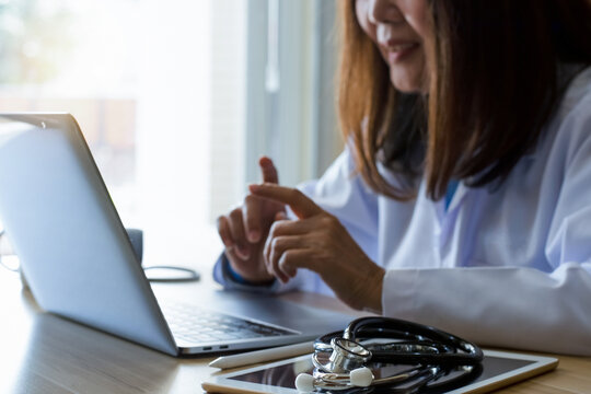 Female Doctor Meeting Patient Virtually, Online Video Call On Laptop Computer With Digital Tablet And Stethoscope On The Table At Office. Telemedicine, Telehealth Concept.