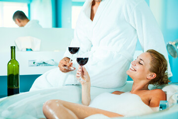 Obraz na płótnie Canvas Couple Enjoying Red Wine in the Bathroom with the foam in the tub. 