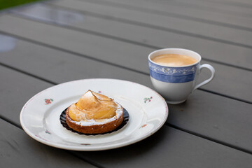 a cup of black coffee with foam, rainy day, sweet tart on a plate
