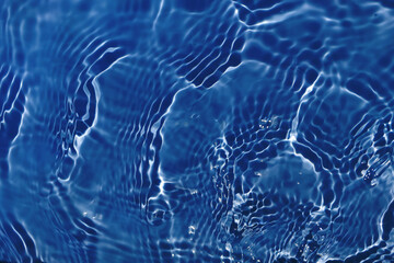 Defocus blurred transparent blue colored clear calm water surface texture with splashes and bubbles. Trendy abstract nature background. Water waves in sunlight with copy space. Blue watercolor shining