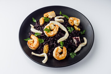 delicious black rice with shrimps and seafood on a white background