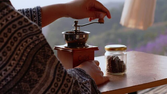 Woman hand grinding coffee bean with a manual coffee grinder