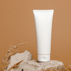 Mockup white plastic cream tube on stone with dry pampas grass. Eco skincare, container for facial...