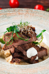 Grilled beef tongue with celery puree and horseradish, closeup.