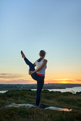Mature healthy woman in yoga class doing exercise outdoor. vertical image with copy space
