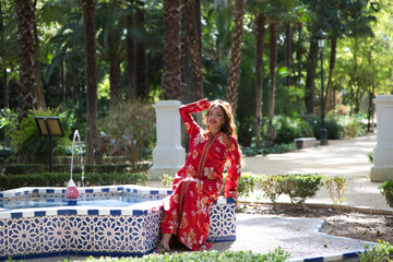 A beautiful Moroccan woman is wearing a traditional Moroccan red dress with gold and silver...