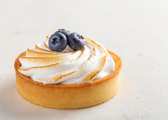 Delicious lemon pie covered with sweet meringue and decorated with blueberries, light background