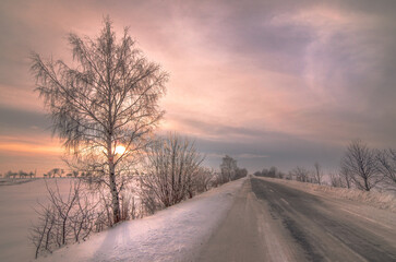 Scenic view of empty road with snow covered tree landscape while snowing in winter season. Beautifull sunset with cloudy sky in Ukraine - 548252738