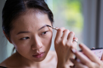 Asian woman tinting and brushing eyebrows in salon