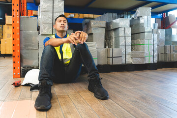 Asian male warehouse staff worker manage factory products goods and shipping to customer. Tired...