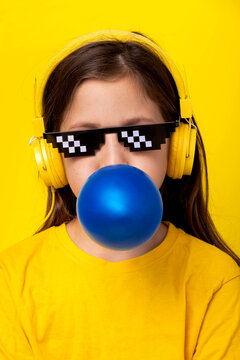 Girl in blue headphones and pixel glasses blowing bubble gum
