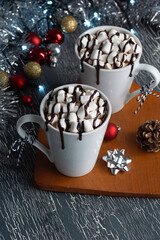Hot Chocolate or Cocoa with Marshmallows Covered in Chocolate Sauce in Two Mugs with Festive Christmas Decorations	