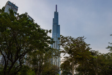 Obraz premium Ho Chi Minh City, Vietnam - November 08, 2022: Landmark 81, a building in Saigon. Landmark 81 among other high-rise buildings of Vinhomes Central Park urban area with a lawn and palm tree alley