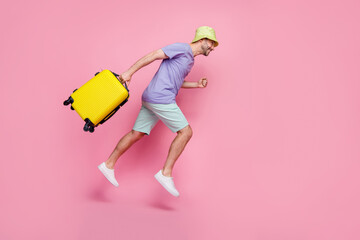 Full body photo of nice young guy jump run empty space crazy traveler baggage dressed trendy blue look isolated on pink color background