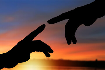 Silhouette of reaching, helping hands, hope and mutual support. Friendship. Sunset background.