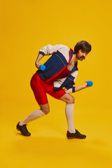 Fototapeta na wymiar Portrait of stylish man with moustache posing in vintage sportswear training with dumbbells isolated over yellow background. Strong hands