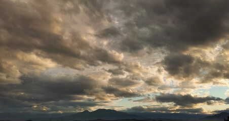 Grandi nuvole nere illuminate dal sole in cielo sopra i monti Appennini al tramonto