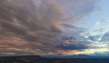 Naklejka na ściany i meble Nuvole enormi e colorate al tramonto sopra le montagne le colline e le valli degli Appennini