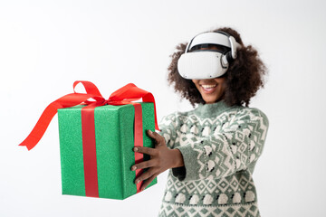 Portrait of young attractive african american woman curly hair with VR goggles holding gift box in studio on white background.