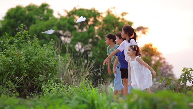 Cute asian little girl playing with paper plane toy with her siblings