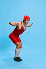 Portrait of stylish man with moustache posing in vintage swimsuit preparing to jump into water isolated over blue background