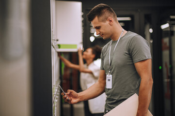 Concentrated office worker and his female colleague opening section lockers