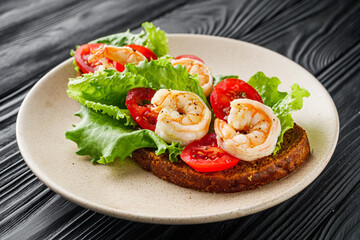 delicious Italian bruschetta with shrimps on a black wooden rustic background