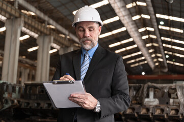 Caucasian senior engineer manager working with clipboard at factory 